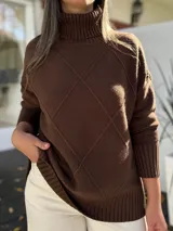 Polerón de tejido de punto color chocolate, con cuello alto y diseño de rombos en relieve en el frente. Presenta mangas largas con puños acanalados y un corte holgado con terminación acanalada en el ruedo.