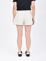 Short negro de tela de buzo, con cintura elástica ajustable con cordón y bolsillos laterales. El ruedo tiene una abertura lateral.