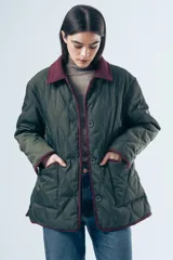 Campera acolchada de diseño matelasse con pespuntes ondulados, cuello clásico en contraste y cierre frontal con botones. Presenta bolsillos frontales con ribetes a tono y calce relajado.
