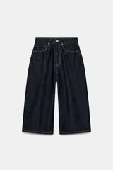Bermuda baggy de denim azul oscuro con tiro medio, trabillas, cinco bolsillos y costuras en contraste. Cierre frontal con cremallera y botón metálico.