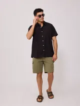 Camisa de manga corta color negro, con cuello clásico y cierre frontal de botones.