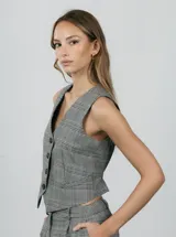 Chaleco sastrero gris con estampado a cuadros, escote en V y cierre frontal con botones.
