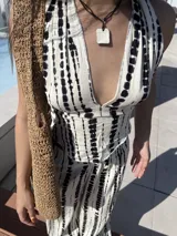 Conjunto de dos piezas compuesto por un top halter con escote en V y un pantalón de corte recto y tiro alto. Ambas prendas presentan un estampado vertical de puntos negros sobre fondo blanco.