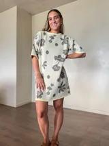 Vestido corto de tejido de punto de algodón con lurex, corte holgado, mangas cortas y cuello redondo, con diseño estampado floral y de lunares en tonos gris y lila sobre base beige claro.