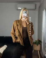 Campera tipo bomber confeccionada en gamuza, con cierre frontal metálico y detalle de flores bordadas en relieve en el frente.