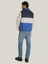 Chaleco acolchado Tommy Hilfiger con diseño triblock en azul marino, gris y azul. Cuenta con cuello alto, cierre de cremallera frontal, dos bolsillos laterales con cremallera y logo bordado en el pecho.