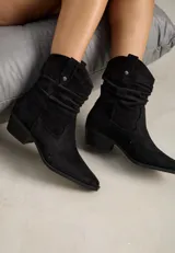 Bota texana de caña corta confeccionada en gamuza negra, con diseño fruncido en el empeine, punta fina y taco cuadrado bajo.