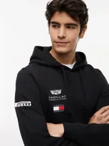 Buzo con capucha y cordón ajustable, confeccionado en algodón. Presenta un diseño de corte regular con bolsillo tipo canguro, puños y bajo de punto canalé. Incluye logos de la colaboración Cadillac Formula 1 Team y Tommy Hilfiger en el pecho, además de detalles distintivos en la manga y la nuca.