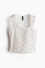 Musculosa de punto de algodón con escote cuadrado, ajuste ceñido y detalle de ribete picot en cuello y sisas. Presenta un estampado de enredaderas florales sobre fondo beige.