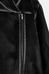Chaqueta de corte biker con cuello solapa, manga larga y cierre frontal cruzado con cremallera. Presenta bolsillos de vivo en el delantero y detalles de costuras a contraste.