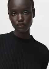 Jersey negro de punto de canalé con cuello caja, manga larga y corte peplum acampanado en la cintura.