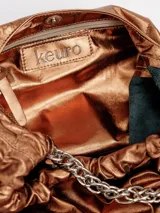 Cartera tipo hobo de cuero metalizado color bronce, con detalles fruncidos en la parte superior y asa de cadena metálica plateada.