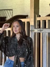 Camisa de lino con estampado orgánico en tonos oscuros, de silueta relajada, mangas amplias y detalle de nudo frontal.