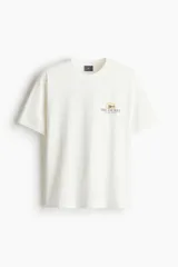 Remera blanca de algodón con cuello redondo y estampado pequeño en el pecho con la frase "Treasures of the Tides" y un dibujo de una concha. Corte holgado.