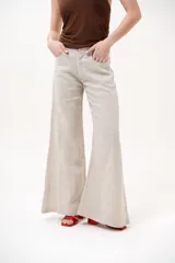Pantalón color beige de corte wide leg, con bolsillos delanteros y cierre frontal de botón y cremallera.