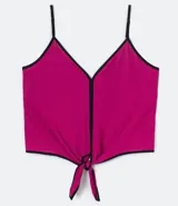 Musculosa cropped fucsia de jersey con estampa de lunares y bordes negros en contraste, escote en V, tirantes finos regulables y detalle de nudo frontal.
