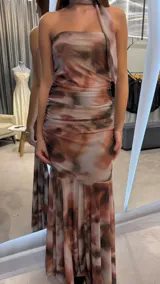 Vestido largo strapless con diseño estampado estilo abstracto en tonos marrones y beige, con detalle de bufanda o lazo al cuello del mismo género y corte sirena con caída fluida.