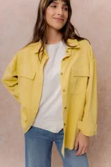 Camisa oversize de denim liviano color amarillo, con cuello camisero, mangas largas con puños, bolsillos delanteros con tapa y ruedo desflecado.