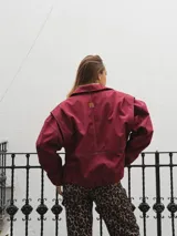 Campera gris con cierre frontal, cuello camisero y mangas largas con puños elásticos.