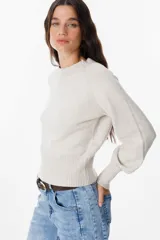 Sweater de punto color crudo con cuello redondo, mangas largas con puños anchos acanalados y cintura también acanalada. Presenta un diseño de silueta holgada y mangas con volumen.