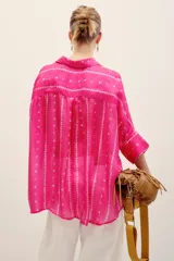 Camisa de seda negra con estampado geométrico de líneas verticales con rombos pequeños en tonos claros, cuello camisero, mangas largas con tajitos en los puños y cierre frontal con botones.