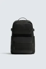 Mochila técnica de color negro con múltiples compartimentos, incluyendo dos bolsillos frontales con cierre, bolsillos laterales y compartimento principal acolchado para dispositivos electrónicos. Cuenta con parte posterior acolchada, banda de sujeción para equipaje, asa de mano y asas de hombro ajustables.