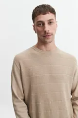 Buzo de punto color beige, con cuello redondo y mangas largas. Tejido con textura piquet y puños acanalados. Corte regular.