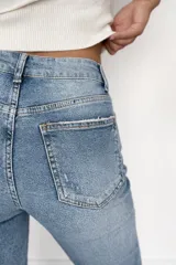 Pantalón de jean corte regular fit en color celeste claro. Presenta un diseño con pequeñas roturas frontales y botamanga con doblez, confeccionado en denim con elastano para mayor flexibilidad y comodidad.