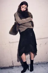 Falda corta negra con efecto metalizado o brillante, cintura elástica y bajo asimétrico con capas superpuestas de tejido ligero.