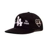 Gorro trucker negro con diseño bordado en color blanco que incluye las letras "LA" al centro y la frase "Mi Casa Su Casa" a los lados.