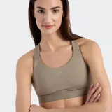 Top deportivo New Balance color beige topo, de soporte medio, con escote redondo y espalda tipo nadador con tirantes ajustables.