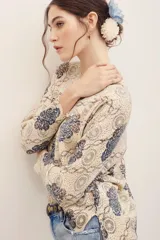 Sweater de punto color beige con estampado geométrico y floral en tonos azules y burdeos, de manga larga y cuello redondo.