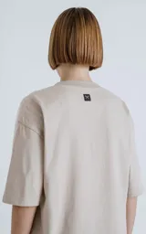 Remera de corte crop y calce oversize, con hombros caídos, confeccionada en algodón premium americano color beige claro. Posee cuello redondo rib al tono y doble costura.