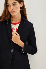 Saco sastrero de denim azul oscuro con costuras a contratono, combinación de forrería en cuerpo y mangas. Tiene botones a tono personalizados en cruce y mangas.