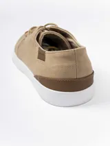 Zapatilla urbana de gamuza sintética color gris, con cordones oscuros, suela de goma blanca y detalles en cuero sintético color suela en el talón y lateral.