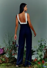 Mono largo azul marino con corte entallado, mangas tipo camiseta, cierre trasero invisible y bolsillos laterales. Presenta detalle de color blanco en la parte superior delantera y trasera.