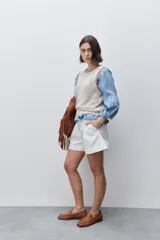 Short de tiro alto confeccionado en algodón, con calce relajado y silueta recta. Presenta pinzas delanteras, bolsillos laterales y botones decorativos en la cintura.