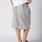 Bermuda sastrera gris de corte baggy, con pinzas al frente y diseño holgado que se extiende por debajo de la rodilla.
