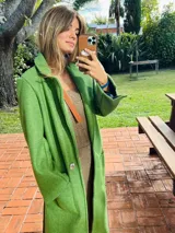 Tapado largo color verde con solapas, bolsillos laterales y cierre con botones.