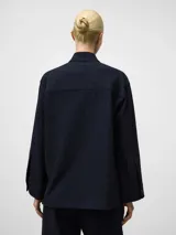 Sobrecamisa de corte boxy fit en color azul marino con diseño de rayas verticales sutiles. Presenta cuello tipo tira, cierre frontal oculto por solapa y mangas largas con puños. Confeccionada en una mezcla de poliéster, viscosa y elastano con textura suave y ligera.