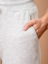 Pantalón tipo babucha de corte deportivo, color beige, con cintura elástica ajustable mediante cordón, puños en los tobillos y bolsillos frontales.