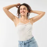 Camiseta de tirantes color blanco, con tejido de punto calado, detalles de encaje en el escote y tirantes finos regulables.