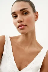 Top de punto canalé en color beige, con escote en pico adornado con una delicada aplicación de encaje blanco y tirantes anchos.