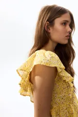 Top de algodón amarillo con estampado floreado, escote corazón, volados en los hombros y detalle de peplum en la cintura.