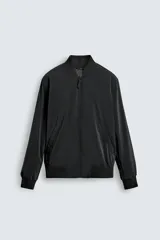 Cazadora bomber ligera de tejido técnico color verde oliva, con cuello, puños y bajo en rib elástico. Presenta cierre frontal de cremallera y bolsillos de vivo en la cadera.