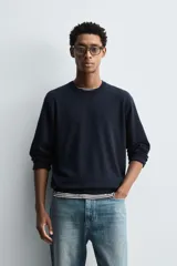 Jersey de punto color azul marino, con cuello redondo y manga larga. Presenta acabados en rib en cuello, puños y bajo.
