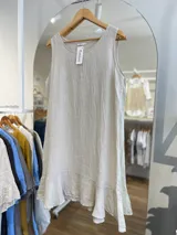 Vestido corto sin mangas, color gris topo, con escote redondo y detalle de volado en el ruedo. El tejido presenta una textura arrugada característica del lino.