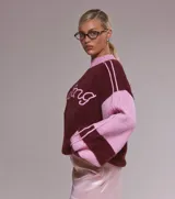 Sweater oversize de punto suave en combinación bicolor bordó y rosa, con cuello redondo tejido y estampa frontal con la palabra Darling en tipografía cursiva.
