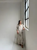 Vestido largo beige con diseño estampado de flores, cuello redondo amplio y mangas largas holgadas.