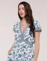 Vestido maxi de rayón con estampado floral en tonos azules y marrones sobre base blanca, con escote en V, mangas cortas y falda larga fluida con volado en el ruedo.